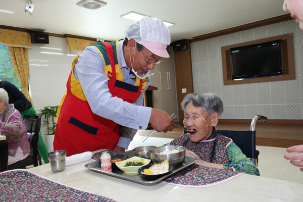 ▲ 허엽 사장이 몸이 불편한 할머니에게 음식을 떠 드리고 있다