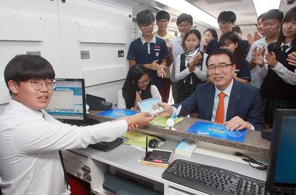 ▲ 조용병 신한은행장이 ‘1사1교 금융교육’의 일환으로 22일 관악구 소재 성보중학교를 방문해 학생 들과 함께 은행과 동일한 환경의 이동점포 뱅버드에서 고객 역할을 하며 금융체험교육을 진행하고 있다. ⓒ 신한은행