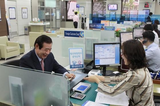 ▲ 대통령 직속 국민대통합위원회 한광옥 위원장이 30일 오전 10시 서울 광화문 인근 신한은행 지점에서 청년희망펀드 가입신청서에 서명한 뒤 통장을 살펴보고 있다. ⓒ국민대통합위원회 제공