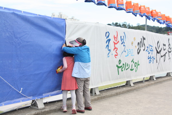 ▲ 지난 10월1일 저녁 8시경 2015 진주남강유등축제에 입장하지 못한 시민들이 펜스 외곽에서 불꽃놀이를 구경하고 있다