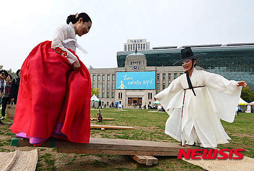 ▲ 22일 오후 서울 중구 서울광장에서 열린 '2015 서울 문화원 엑스포' 민속 전통놀이 체험마당에서 한복을 입은 시민들이 널뛰기 체험을 하고 있다.     ⓒ 뉴시스