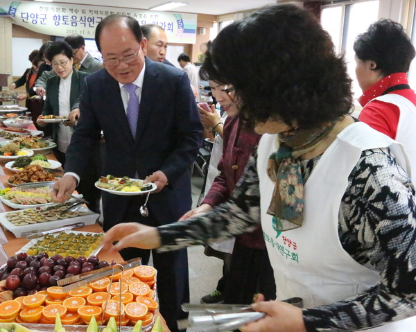 ▲ 류한우 단양군수(가운데)가 향토음식 전시회에서 맛을 보기 위해 접시에 음식을 담고 있다. 사진제공=단양군