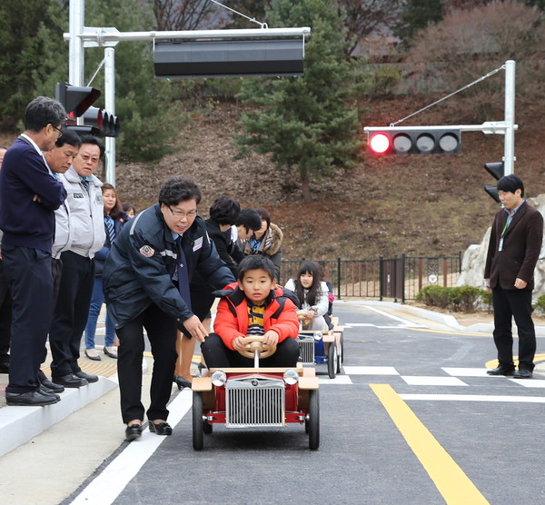 ▲ 어린이들이 교통안전체험장에서 모범운전자들의 도움을 받으며 전동차로 건널목을 건너고 있다.사진제공=충주시