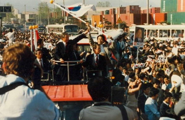 1987년 대선 당시 백만 군중이 운집한 부산 수영만 유세에서 통일민주당 김영삼 후보(당시)가 무개차 위에서 손을 흔들고 있는 가운데, 새누리당 김무성 대표가 곁에서 태극기를 힘차게 휘두르고 있다. ⓒ김무성 대표 블로그 캡쳐