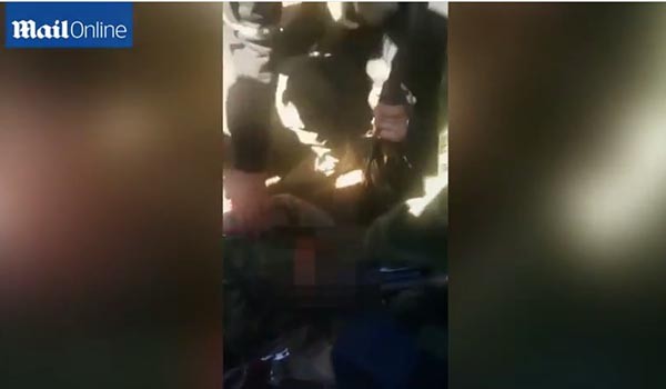 ▲ 투크르멘 반군들이 자신들의 공격으로 사망한 러시아 조종사의 시신을 중앙에 두고 떠드는 모습. 실제 원본에는 숨진 러시아 조종사의 모습이 그대로 드러난다. ⓒ英데일리 메일 온라인이 유튜브에 공개한 관련 영상 캡쳐
