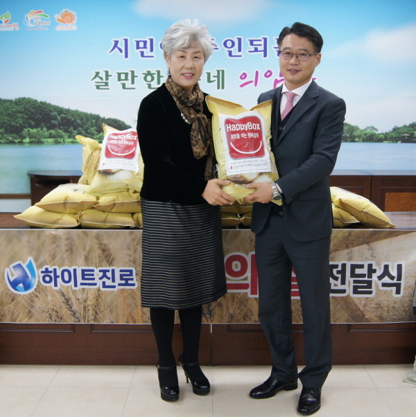 ▲ 하이트 진로가 제천시 의암동 주민자치위원회에 쌀을 전달하고 있다.사진제공=제천시