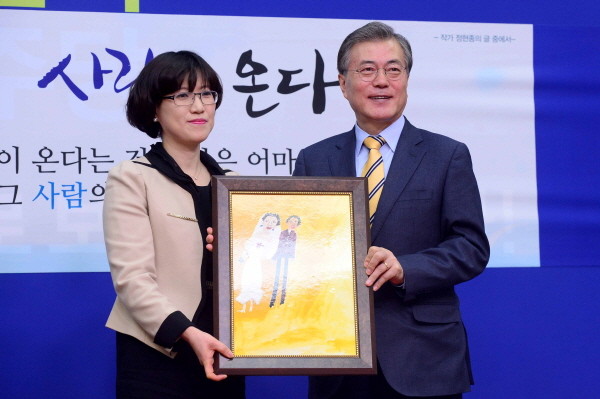 ▲ 더불어민주당 문재인 대표가 지난 6일 김선현 차의과학대학교 교수 입당식에서 위안부 피해 할머니의 그림을 전달받고 있다. 김선현 교수는 이처럼 위안부 피해 할머니들의 그림을 무단으로 사용해왔다는 독직 의혹에 휩싸여 있다. ⓒ뉴시스 사진DB