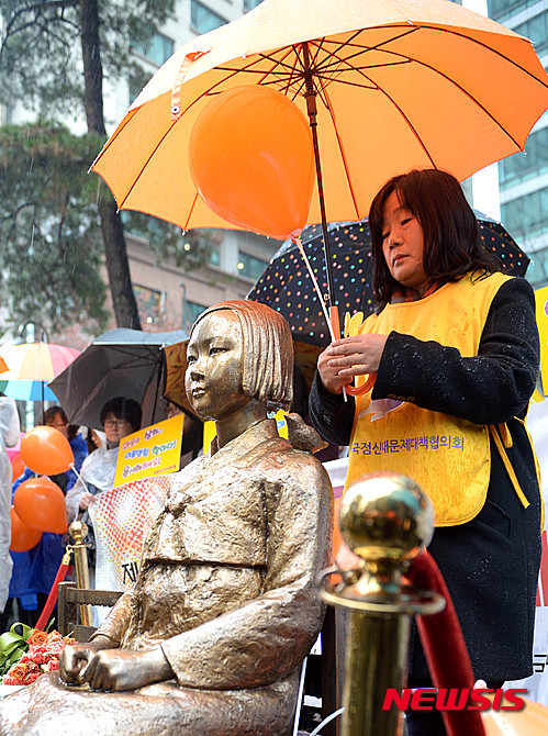 일본군 위안부 문제해결을 위한 정기 수요시위에 윤미향 정대협 상임대표가 평화의 소녀상에게 우산을 씌워주고 있다.  ⓒ 뉴시스