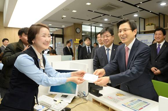 ▲ 황교안 국무총리(사진 오른쪽)가 14일 농협은행 대전중앙지점을 방문해 ISA에 가입하고 있는 모습.ⓒNH농협은행