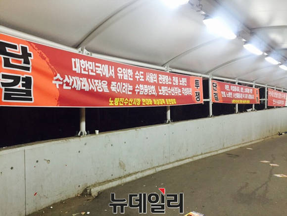 ▲ 노량진 수산물 도매시장이 16일 새벽 1시 현대화 시장에서의 첫 경매를 시작으로 개장을 알린 가운데 시장 앞 통로에 입주반대 현수막이 걸려있다. ⓒ 뉴데일리 김희진 기자