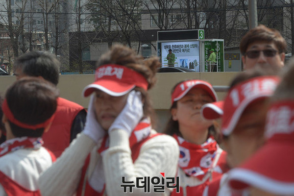 ▲ 새누리당 김효재 후보의 출정식이 진행되는 중간 국민의당 유세차량이 지나가며 유세를 하자 한 유세단원이 귀를 막고 있다. ⓒ뉴데일리 정재훈 기자