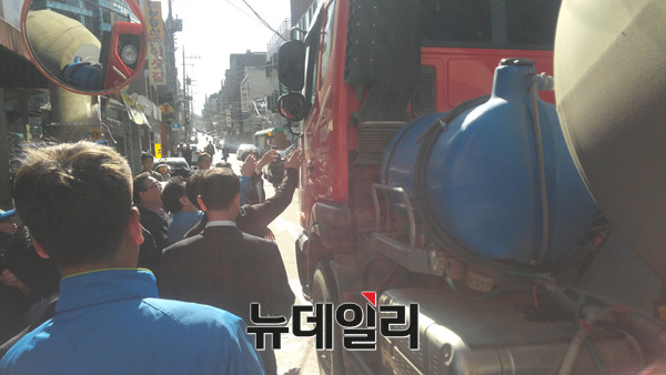 ▲ 4일 더불어민주당 김종인 대표의 지원유세 중에 소동이 일어났다. 유세현장을 가로지르는 레미콘 차량의 운전사와 관계자가 마찰을 일으킨 것이다. 사진은 레미콘 차량 운전사를 향해 관계자들이 저마다 손을 들고 한 마디씩 하는 모습. ⓒ뉴데일리 임재섭 기자