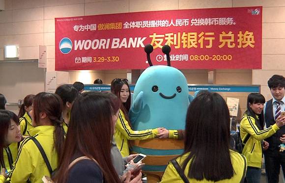 ▲ 지난 3월 인천 송도컨벤시아에 설치한 우리은행 임시환전소에 몰려든 유커들이 우리은행 모바일전문은행 브랜드 ‘위비’ 인형과 함께 기념사진을 찍고 있다. ⓒ우리은행