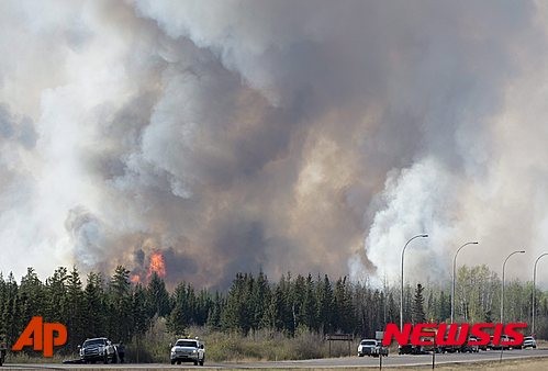 ▲ 캐나다에서 초대형 산불이 확산되는 가운데 피난길도 한때 통제되는 상황이 벌어진 것으로 전해졌다. 구조 당국은 6일(현지시간) 앨버타주 포트 맥머레이에서 남쪽으로 빠져나가는 63번 국도 인근에 불길이 치솟아 피난 차량 호위 작전이 약 1시간 정도 중단됐다가 재개됐다고 밝혔다. 63번 국도로 주민들이 차로 대피하는 모습 ⓒAP 뉴시스