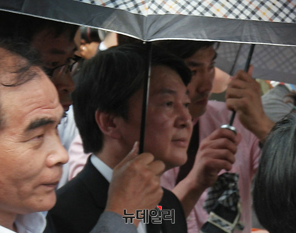 ▲ 국민의당 안철수 대표가 23일 경남 김해 봉하마을에서 폴리스라인에 의지해 우산을 받쳐들고 추도식장을 빠져나가고 있다. ⓒ김해(경남)=뉴데일리 정상윤 기자