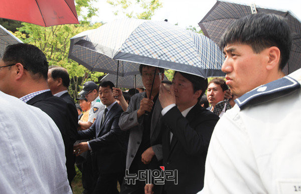 ▲ 국민의당 안철수 대표가 23일 경남 김해 봉하마을에서 폴리스라인에 의지해 우산을 받쳐들고 추도식장을 빠져나가고 있다. ⓒ김해(경남)=뉴데일리 정상윤 기자