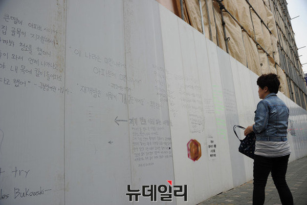 ▲ 26일 오후 무악2지구 재개발 현장에서 한 시민이 가림막에 쓰인 낙서들을 보고 있다. ⓒ정재훈 뉴데일리 기자
