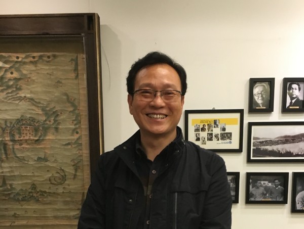 ▲ 거북선호텔 프런트에 선 설종국 대표. 오른쪽에 박경리 김춘수 유치환등 통영출신 문화인들 사진들. 왼쪽엔 가장 오래된 통영 고지도.