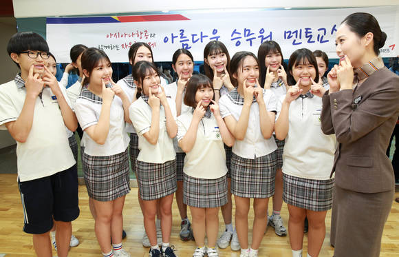 ▲ 지난 20일 '아름다운 승무원 멘토 교실'에서 아시아나항공 승무원이 학생들에게 미소 짓기 교육 실시하고 하고 있다.ⓒ아시아나항공