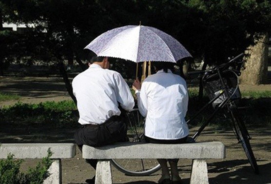 ▲ 조용한 곳에서 우산을 쓰고 이야기를 나누는 북한의 남녀 / 동아일보 DB