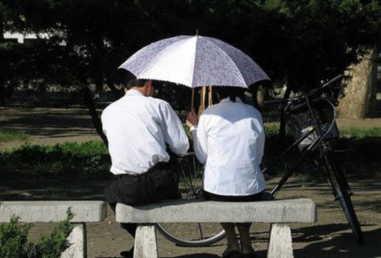 ▲ 조용한 곳에서 우산을 쓰고 이야기를 나누는 북한의 남녀 / 동아일보 DB