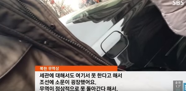 ▲ 중국 금융당국이 북한 은행 간의 거래를 전면 중단함에 따라 최근 북측 무역상들이 울상인 것으로 알려졌다. 사진은 북한과 중국의 무역 관문인 단둥의 한 북측 무역상이 대북 송금 차단과 관련해 이야기 하고 있는 모습.ⓒSBS중계영상 캡쳐