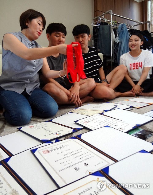 ▲ 2016 리우데자네이루 올림픽에서 금메달을 딴 남자 펜싱 박상영(21·한국체대) 선수 어머니 최명선(51) 씨가 경남 진주 자택에서 박 선수가 어릴 적 땄던 우승 상장과 메달 등을 박 선수의 형 상훈(25·왼쪽 두번째))씨와 그의 친구들에게 소개하고 있다.  ⓒ 연합뉴스