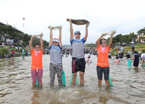 ▲ 4일 괴산군이 주최한 괴산고추축제의 일환으로 열린 물고기잡기대회에서 한 가족이 모두 물고기를 잡고 기뻐하고 있다.ⓒ괴산군