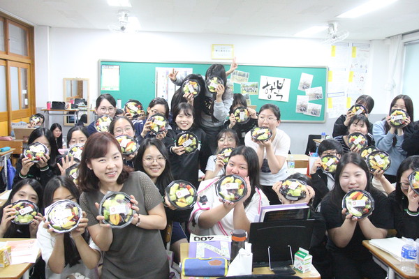 ▲ 화여고 3학년5반 학생들과 담임 박성천교사(여·사진 앞줄 왼쪽서 세 번째)가 2일 오후 교실에서 수성대학교의 ‘수험생 힘내라 힘!’ 이벤트 과일도시락을 받고 파이팅을 외치고 있다.ⓒ수성대 제공