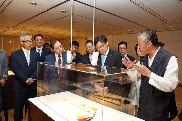 ▲ ‘세대를 잇는 작업-이음展 장도장’ 전시회에 출품된 박종군 장도장의 작품 '백옥금장환별자리금상감보검'을 감상하고 있는 서도식 한국문화재재단 이사장, 정춘모 중요무형문화재 제4호 갓일보유자, 권오준 포스코 회장, 박종군 중요무형문화재 제 60호 장도장보유자(맨 앞줄 왼쪽부터). ⓒ포스코