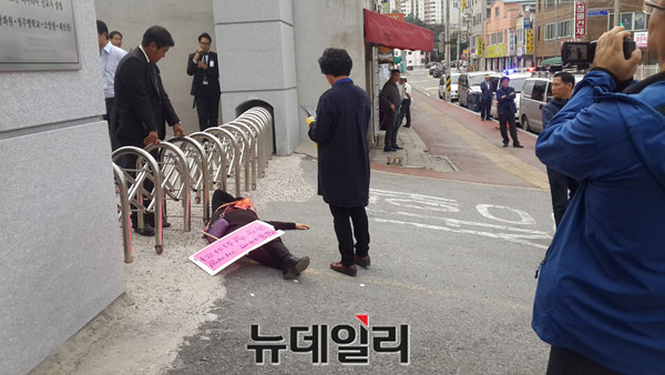 ▲ 충북 청주시 탑동2구역 재개발에 반대하는 한 주민이 30일 관리처분총회가 열리는 청주맹학교 정문앞에 드러누워 시위를 벌이고 있다.ⓒ김종혁 기자