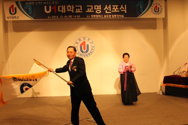 ▲ 채훈관 유원대학교 총장이 설립자 김맹석 여사로부터 교기를 넘겨받아 흔들고 있다.ⓒ유원대학교