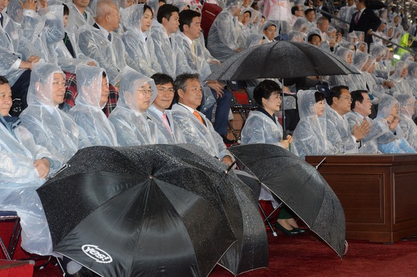 ▲ 박근혜 대통령과 안희정 충남도지사 등 주요 내빈들이 우비를 입은 채 우산을 받쳐들고 개막행사를 관람하고 있다.ⓒ충남도