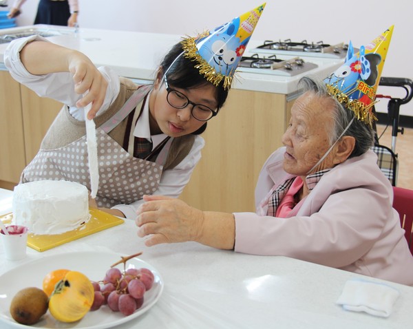 ▲ 다솜학교 학생과 제천시노인복지회관 어르신이 함께 생일케이크를 만들고 있다.ⓒ다솜학교
