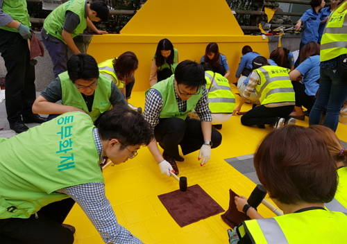 ▲ 동부화재 임직원과 PA들이 마포 염리초등학교에서 옐로카펫 설치 작업을 진행하고 있다.ⓒ동부화재