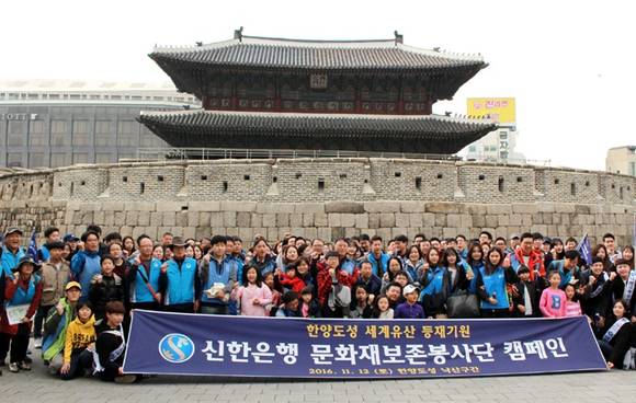 ▲ 지난 12일 신한은행 임직원과 한양도성 시민 순성관들이 흥인지문(동대문)앞에서 한양도성 세계유산 등재 기원 캠페인을 시작하며 파이팅을 외치고 있다. ⓒ신한은행