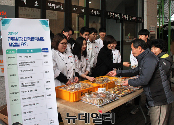 ▲ 대원대 호텔조리계열 제과제빵 학생들과 남혜영 지도교수가 만든 약초 빵 등을 상인과 시민들에게 무료로 나눠 주고 있다.ⓒ목성균 기자