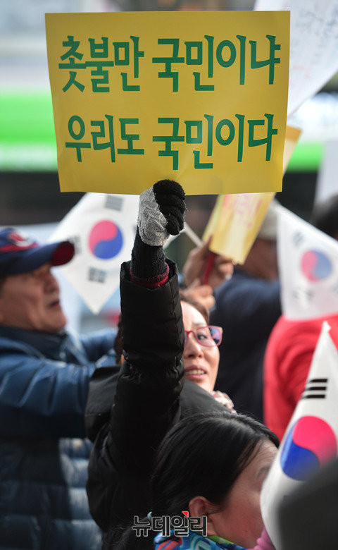 ▲ '촛불만 국민이냐 우리도 국민이다'라는 문구가 담긴 손피켓을 든 시민. ⓒ뉴데일리 정상윤 기자