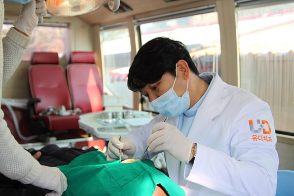 ▲ 진세식 유디치과 강남역점 대표원장이 어르신의 치아를 검진 한 후 치료 하는 모습ⓒ유디치과