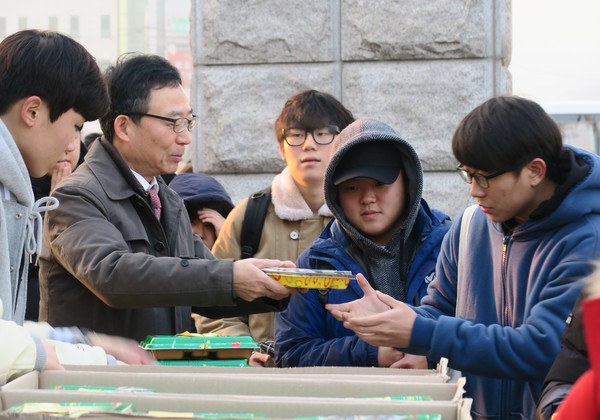 ▲ 김영호 한국교통대 총장(왼쪽 두번째)이 학교 정문 앞에서 학생들에게 도시락을 전달해 주고 있다.ⓒ한국교통대