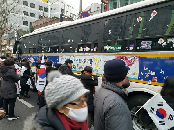 ▲ 박근혜 대통령 퇴진을 촉구하는 촛불집회 측이 붙여 놓은 온갖 종류의 스티커를 일일이 손으로 떼고 있는 '태극기 집회' 참가자들. ⓒ뉴데일리DB