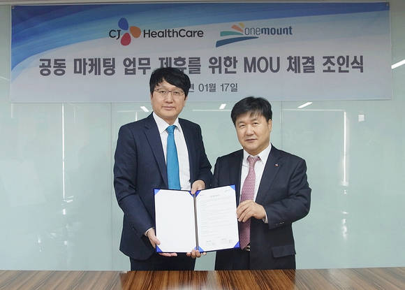 ▲ 원마운트 석준호 대표(좌)와 CJ헬스케어 곽달원 대표(우)가 협약서를 들고 기념촬영을 하고 있다.ⓒCJ헬스케어