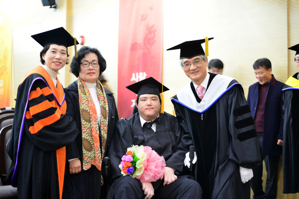 ▲ 루게릭병과 싸우며 입학 5년만에 대학생활을 무사히 마친 전자정보통신공학과 서정재씨가 홍덕률 총장(오른쪽)과 기념촬영을 하고 있다.ⓒ대구사이버대 제공