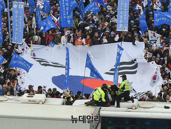 ▲ '3.1절 태극기국민운동 및 구국기도회' 행사 진행 중 경찰 버스 위에 올라간 한 시민이 경찰에 의해 끌려내려가고 있는 모습.ⓒ뉴데일리 정상윤 기자