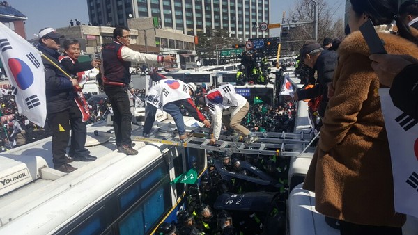 ▲ 헌법재판소의 대통령 탄핵심판 인용 결정이 나온 8일 대통령 탄핵결정에 불복한 시민들이 헌재 앞에 세워진 경찰차벽을 넘어 헌재 진입을 시도하고 있다. ⓒ뉴데일리 이길호 기자