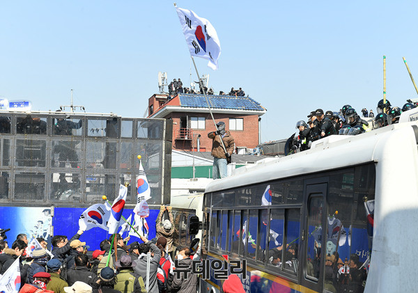 ▲ 헌재의 탄핵결정에 반대하는 경찰버스 위에 올라 태극기를 흔들고 있다. ⓒ 뉴데일리 정상윤 기자