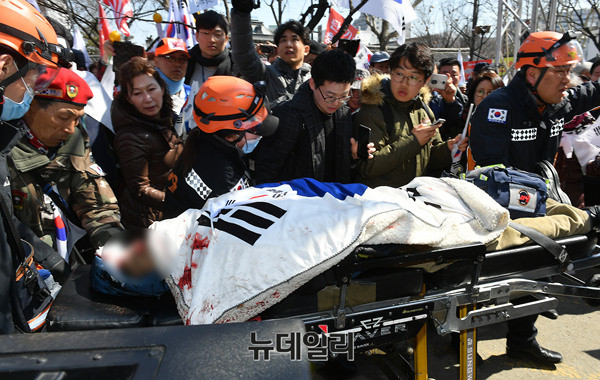 ▲ 10일 정오 무렵 헌재 앞에서 머리에 심한 부상을 입은 김모(72)씨가 병원으로 이송되고 있다. 김씨는 병원으로 옮겨진 직후 숨을 거뒀다. ⓒ 뉴데일리 정상윤 기자