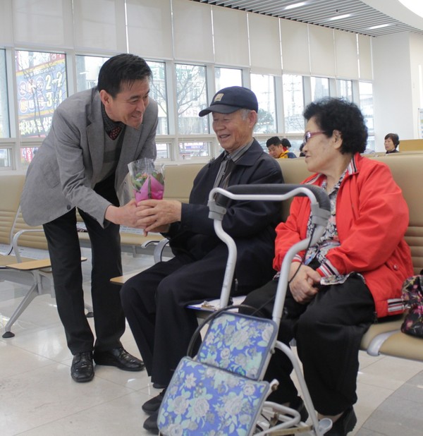 ▲ 김태훈 본부장이 건강검진을 받기 위해 내원한 노부부에게 꽃 화분을 전달하고 있다.ⓒ한국건강관리협회 충북·세종지부