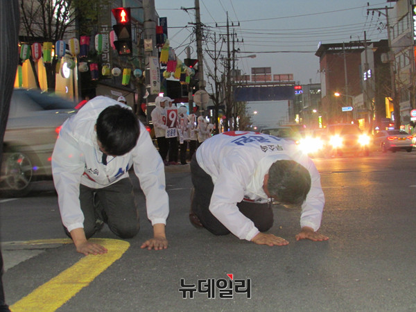 ▲ 무소속 성윤환 후보가 11일 저녁 상주 서문사거리에서 아들과 함께 상주시민들을 향해 아스팔트 바닥에서 큰절을 올리고 있다. ⓒ상주(경북)=뉴데일리 정도원 기자