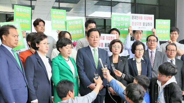 ▲ 국민의당 주승용 원내대표가 25일 충북 음성의 한국고용정보원을 찾은 자리에서 취재진의 질문에 답하고 있는 사이, 청년위원회 관계자들이 뒤에서 피케팅을 진행하고 있다. ⓒ뉴시스 사진DB